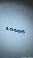 Five loose round blue sapphires on neutral background