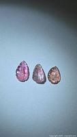three carved pink tourmaline gemstones rowed on white background