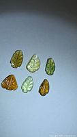 Six multicolored leaf-cut tourmaline stones on neutral background
