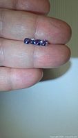 Three cushion-cut tanzanites on fingertips