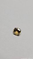 Cushion-cut citrine gemstone on neutral background
