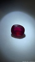 Front angled view of the oval ruby showing red color and facets