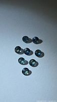 Eight round faceted sapphires displayed on light surface