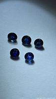 Five round royal blue sapphires on white background