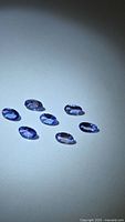 Seven oval violet-blue gemstones on white background