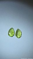Pair of lemon-lime leaf-cut tourmaline gemstones on neutral background