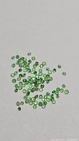 Loose green round-cut tsavorite garnets spread on surface