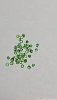 Group of small round green tsavorite garnets on neutral background