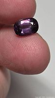Front view of cushion-cut purple spinel held between fingers
