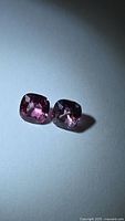 Two cushion-cut pink spinels on neutral background