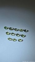 Group of 11 oval lemon lime tanzanite gemstones on neutral background