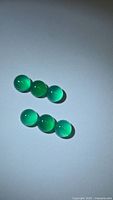 Six vivid green onyx cabochons displayed under spotlight