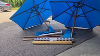 Two blue umbrellas opened with wooden poles, mats and anchor visible