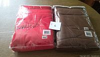 Red and brown fleece blankets sealed in plastic on table with label