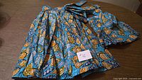 Adult and child matching bright print wrap-around skirts displayed flat with waist ties visible and size card