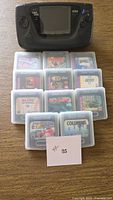 Front view of Sega Game Gear console with 11 game cartridges in clear cases
