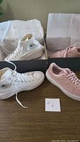 Both pairs of sneakers displayed: Converse white high-tops and Nike pink low-tops