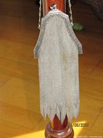 Full view of purse hanging, showing mesh body and fringed bottom