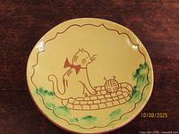 Front of yellow slip redware plate with cat illustration