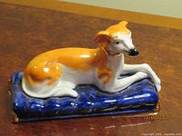 Front and side view of porcelain whippet on blue cushion