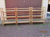 Three assembled wooden shelves side by side outdoors