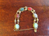 Full view of bracelet laid flat showing all scarabs, links and safety chain