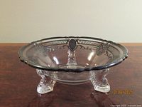 Side view of Heisey dish showing sterling silver overlay trim and three glass feet