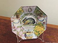 Front view of octagonal John Derian decoupage plate on stand