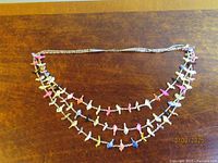 Full view of three-strand pastel bird fetish heishi necklace laid flat