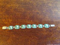 Full view of bracelet laid flat showing all enamel panels and clasp