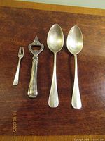 Full view of all four utensils: small fork, bottle opener, two serving spoons