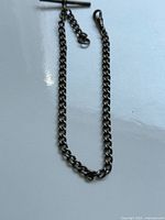 Sterling silver antique watch chain with T-bar and spring ring clasp displayed on white surface