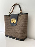 Front view of Enid Collins jute and leather handbag showing brass face clasp