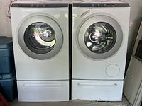 Washer and dryer front view on pedestals