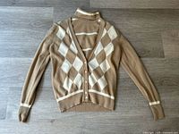 Full view of cardigan laid flat over turtleneck showing overall design and color