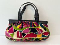 Front view of handbag showing velvet pattern and leather handles