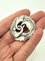 Brooch front view in hand showing scale and design