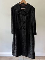Front view of full-length black brocade evening coat on hanger