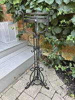 Full view of wrought iron plant stand showing basket top and base