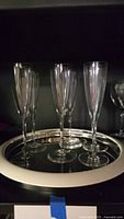 Six Baccarat champagne flutes standing on mirrored Waterford tray