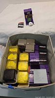 Fabric bin containing stacks of sealed purple and yellow Roblox blind boxes with sample figure and code card shown
