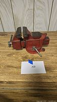 Full view of red Columbian bench vise on wooden surface