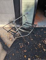Chrome folding luggage rack standing open on driveway