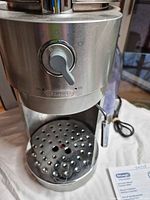 Front view of DeLonghi ES460S espresso maker showing control knob, drip tray and water reservoir