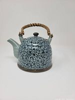 Front view of patterned ceramic teapot with bamboo handle