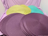 Stacked purple placemats with lime green and teal visible behind