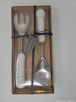 Boxed Pottery Barn marble salad servers, spoon and fork visible through clear lid