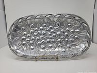 Front view of oval cast aluminum tray showing raised cherries and leaves pattern and pierced rim