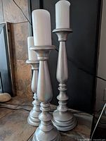 Three silver-tone wooden candle holders with pillar candles for scale