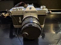 Front view of Bell & Howell FD 35 camera with lens, cap and strap